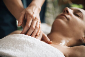 Ayurvedic practitioner massaging female client chest with Ayurveda oil