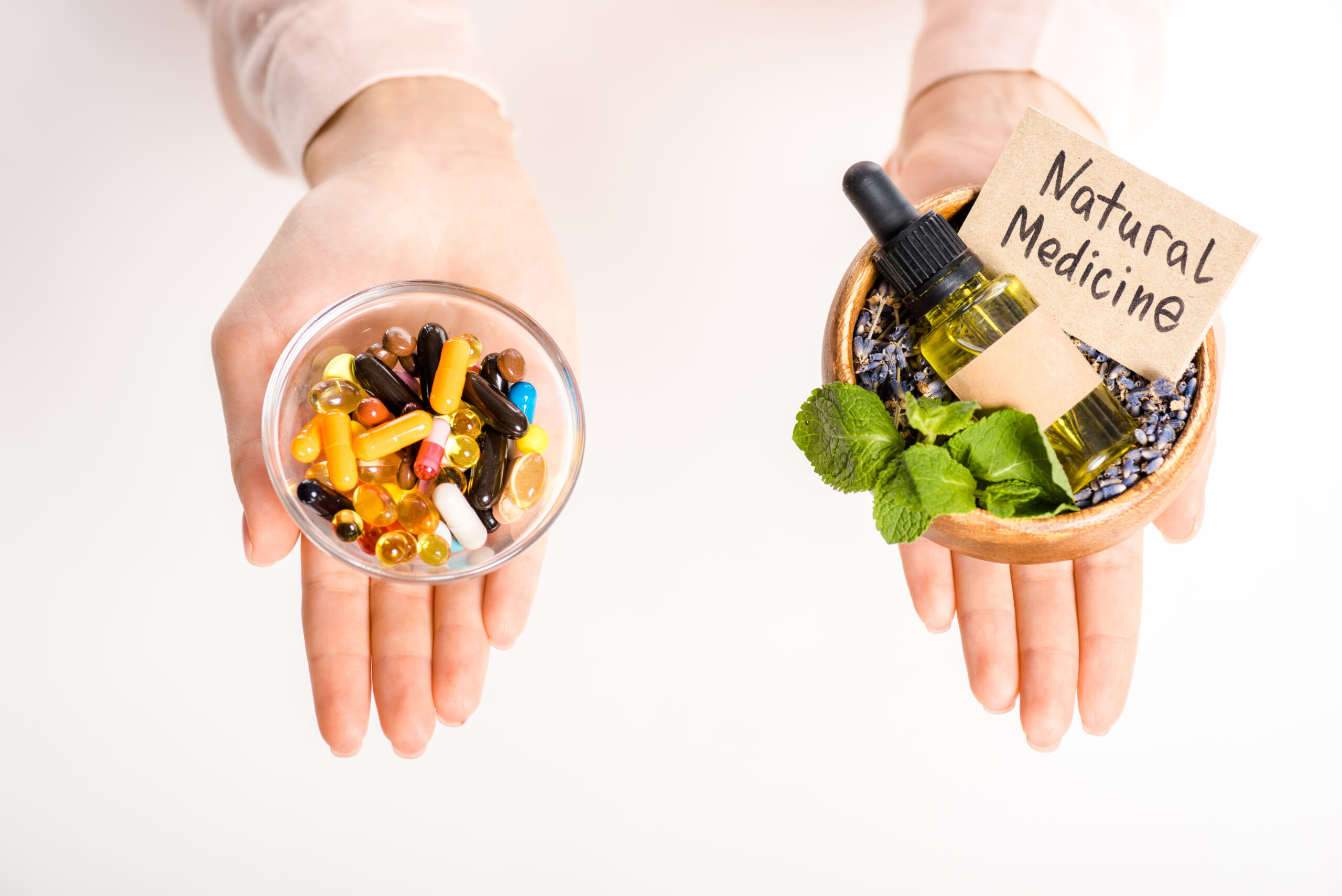 cropped image of woman holding bowls with natural medicine oil and pharmacological pills isolated on